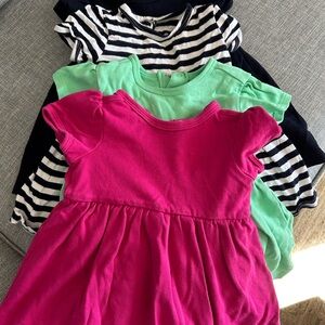 Primary Kids Dresses in Pink, Green, Black, and Black Striped.